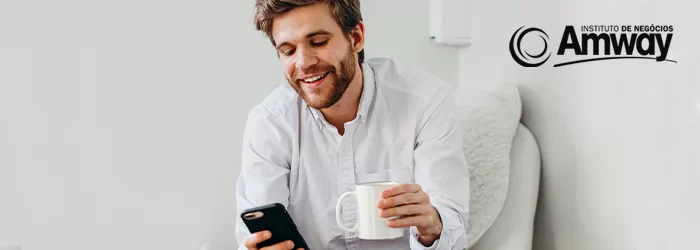 Um jovem segurando o celular e vendo seu escritório virtual amway